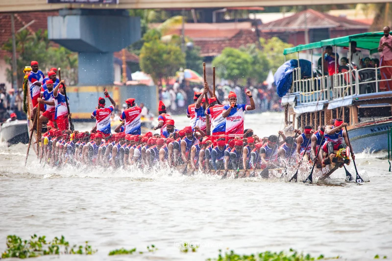 A full snake boat crew racing towards the camera, spray flying