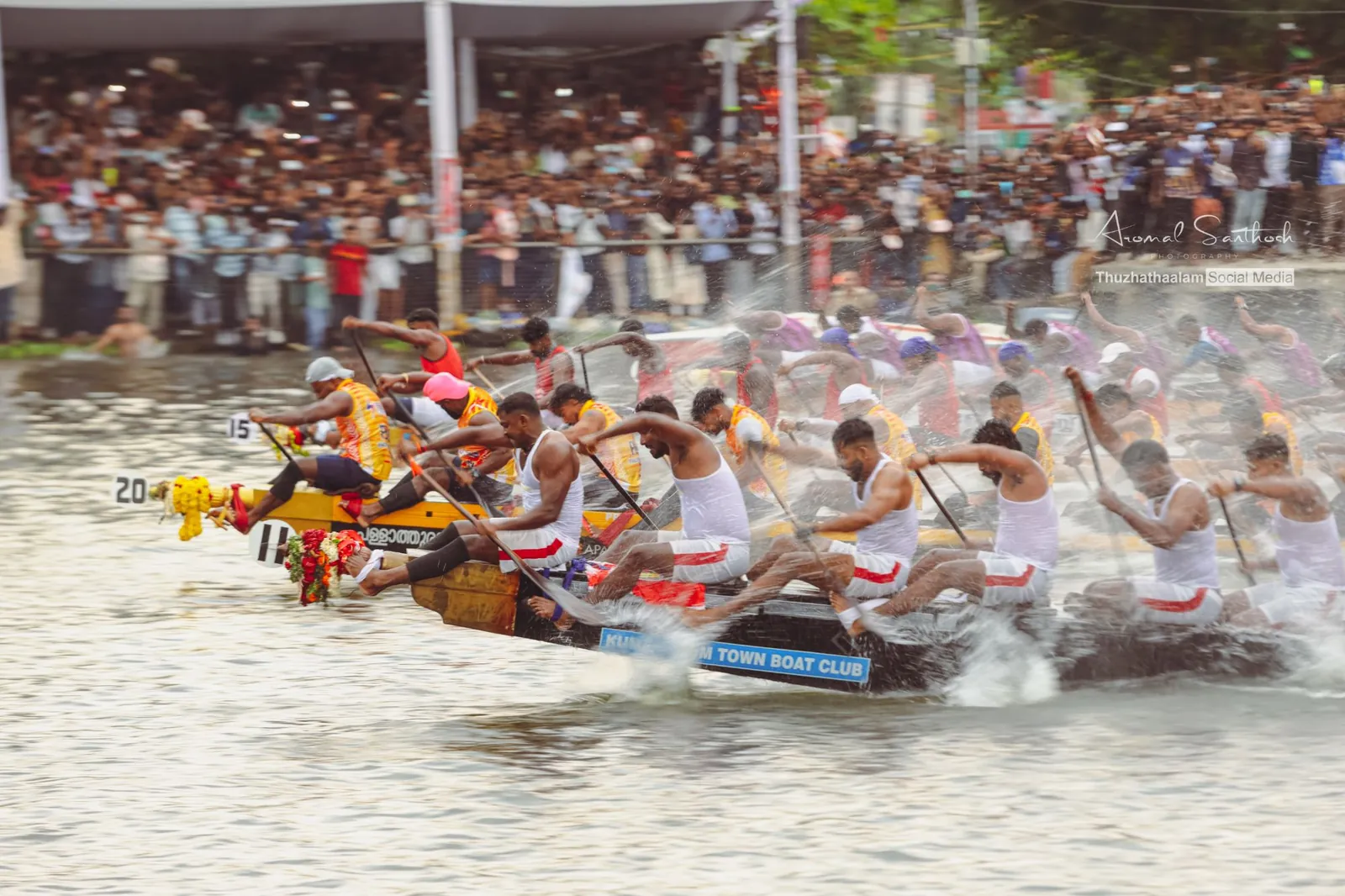 Two snake boats neck and neck in a blur of spray before a packed grandstand