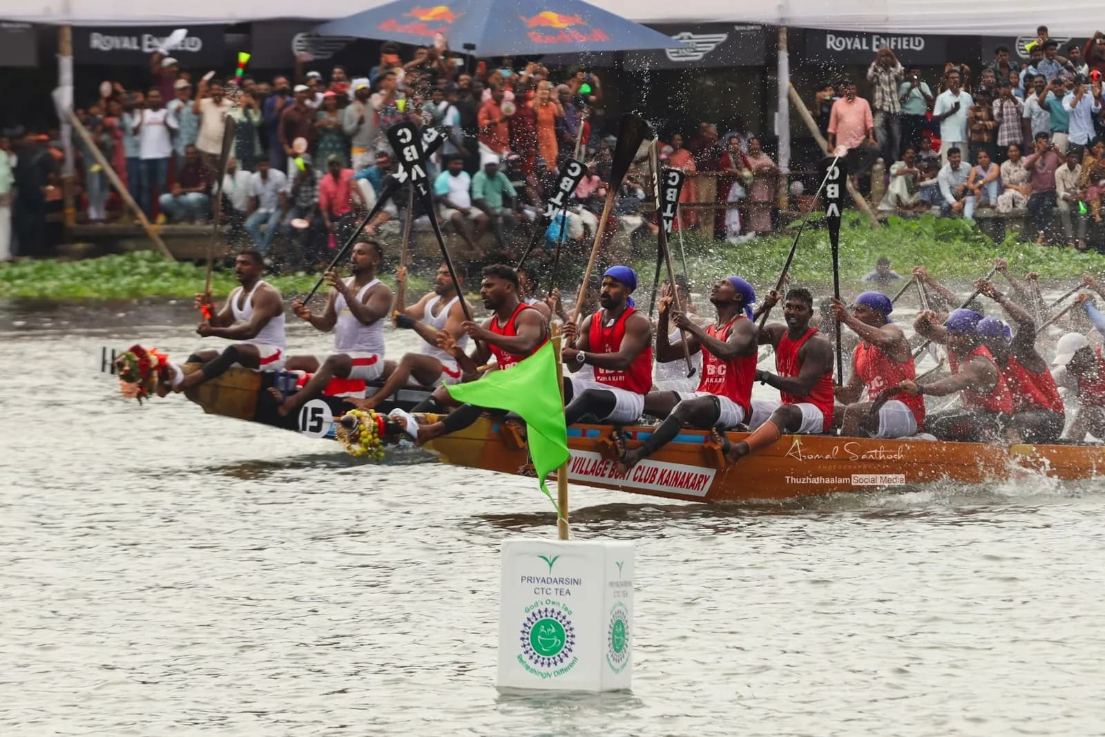 Village Boat Club Kainakary crew raising their paddles past a course marker