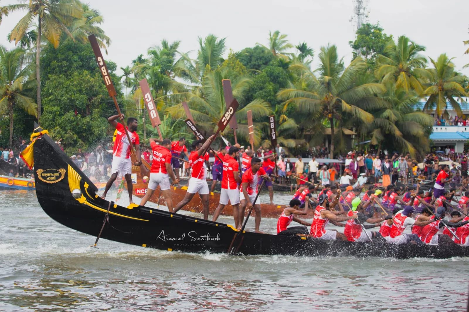 UBC steersmen standing tall on a black snake boat as the crew drives forward